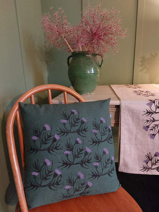 thistles on dark green cushion